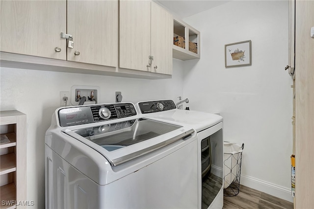 clothes washing area featuring washing machine and dryer, light hardwood / wood-style flooring, and cabinets