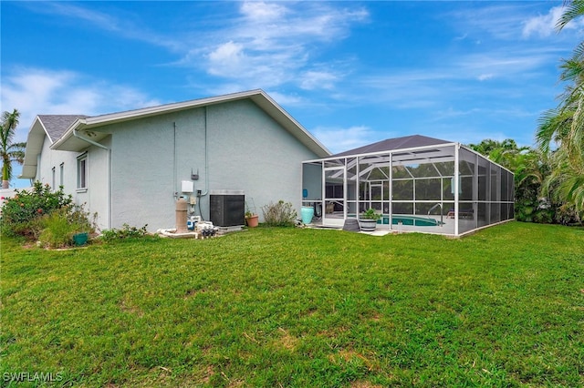 back of property with a lawn, cooling unit, and a lanai