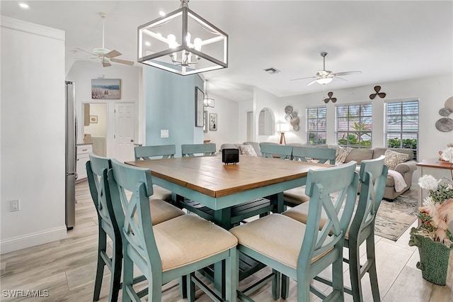 dining space featuring vaulted ceiling, ceiling fan with notable chandelier, and light wood-type flooring