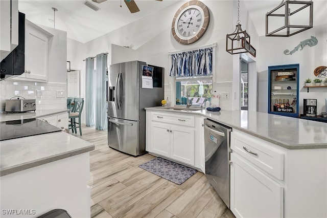 kitchen with tasteful backsplash, decorative light fixtures, light hardwood / wood-style floors, white cabinetry, and stainless steel appliances