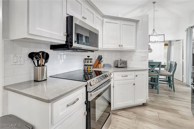 kitchen featuring backsplash, white cabinetry, hanging light fixtures, and appliances with stainless steel finishes