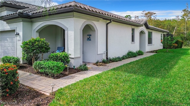 view of exterior entry with a garage and a lawn