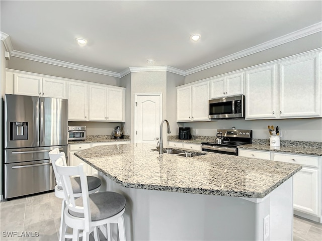 kitchen featuring white cabinets, sink, an island with sink, light stone counters, and stainless steel appliances