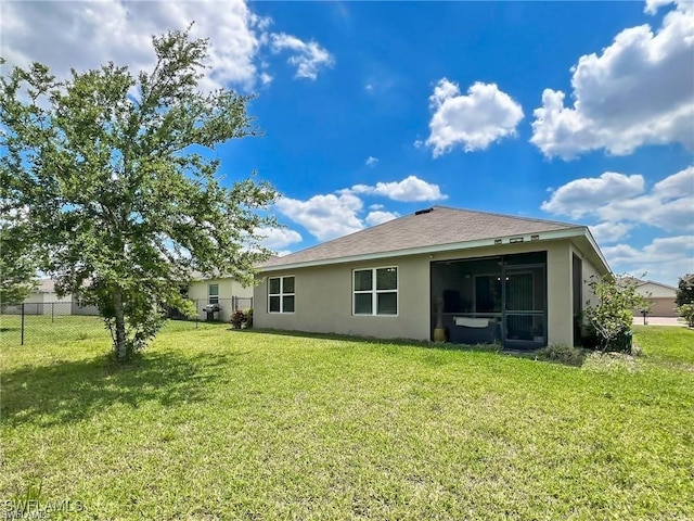 rear view of house with a yard and a sunroom