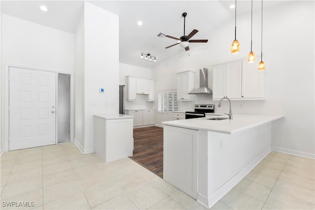 kitchen with white cabinets, sink, stainless steel electric stove, and wall chimney range hood