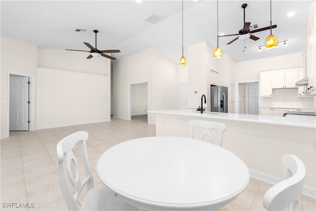 dining room featuring light tile patterned floors, high vaulted ceiling, ceiling fan, and sink