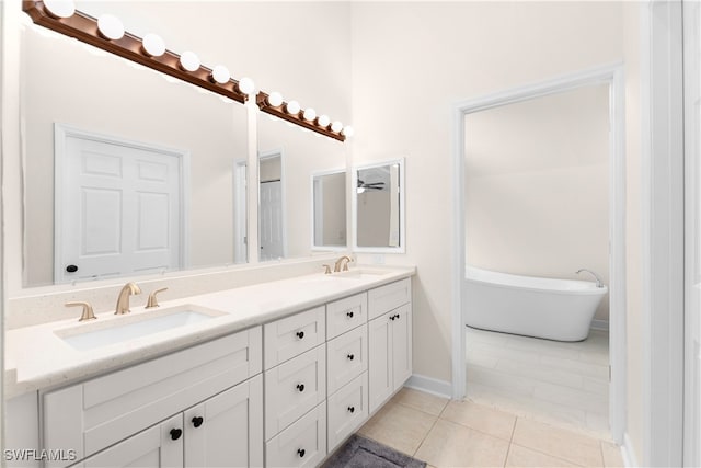 bathroom with tile patterned floors, a washtub, and vanity