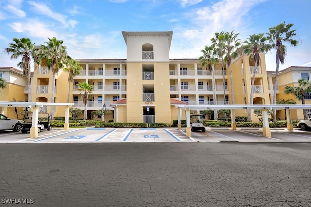 view of building exterior featuring covered and uncovered parking