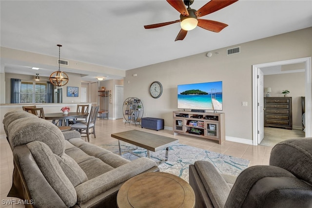 living area featuring ceiling fan with notable chandelier, visible vents, baseboards, and light tile patterned flooring