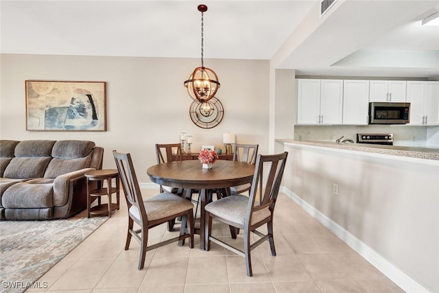 tiled dining room with an inviting chandelier