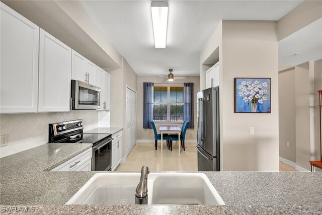 kitchen featuring appliances with stainless steel finishes, light stone counters, white cabinetry, and sink