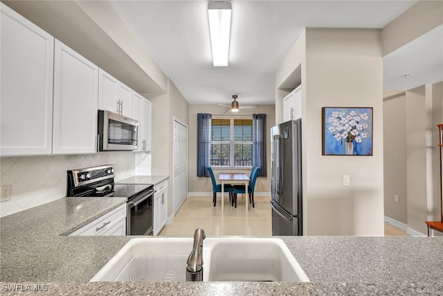 kitchen featuring tasteful backsplash, appliances with stainless steel finishes, white cabinetry, a sink, and ceiling fan