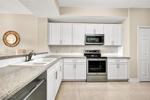 kitchen featuring white cabinets, sink, light tile patterned floors, appliances with stainless steel finishes, and tasteful backsplash