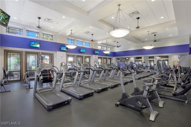 exercise room with a towering ceiling and coffered ceiling