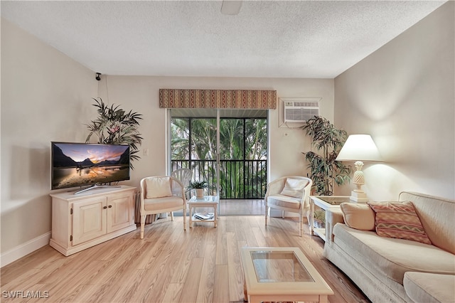 living room featuring a wall mounted air conditioner, a textured ceiling, and light hardwood / wood-style flooring