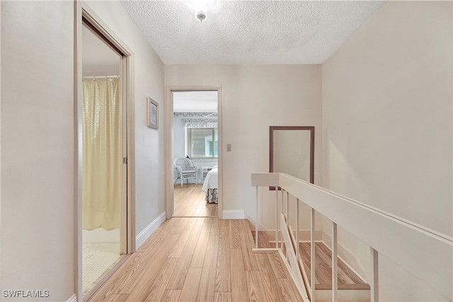 corridor featuring light hardwood / wood-style floors and a textured ceiling