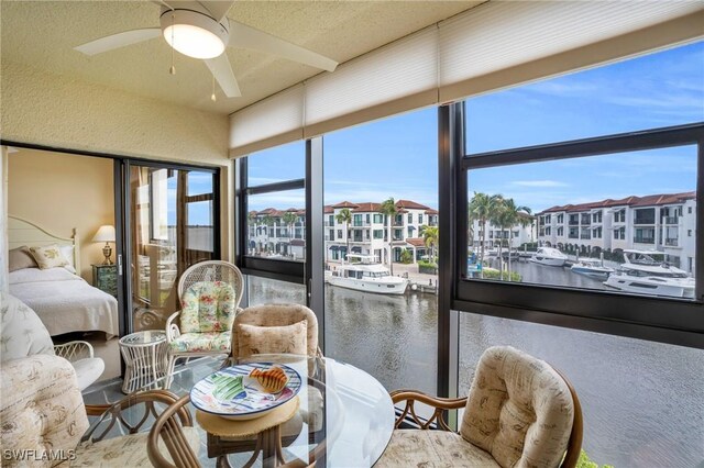 sunroom / solarium featuring plenty of natural light, ceiling fan, and a water view