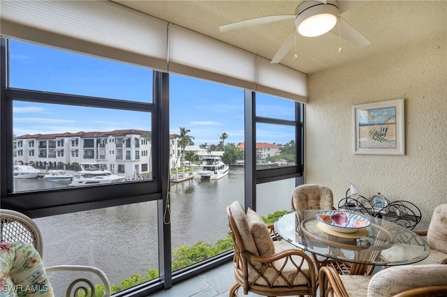 sunroom / solarium featuring a water view and ceiling fan