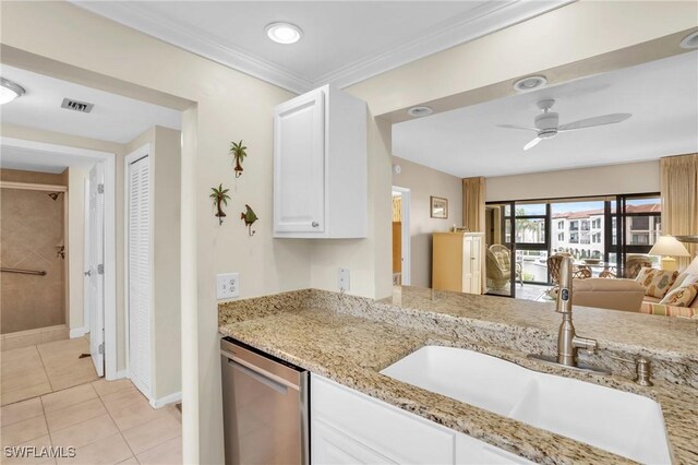 kitchen with light tile patterned flooring, sink, white cabinets, ornamental molding, and light stone counters