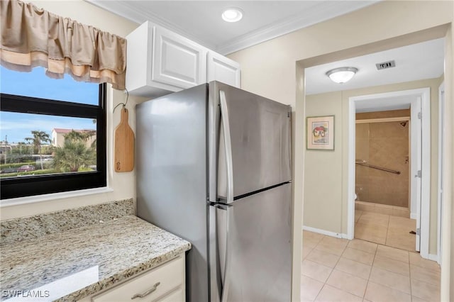 kitchen featuring stainless steel refrigerator, white cabinets, light tile patterned floors, light stone counters, and crown molding