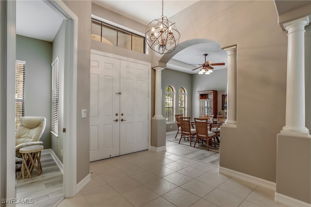 foyer entrance with ceiling fan with notable chandelier and light tile patterned floors