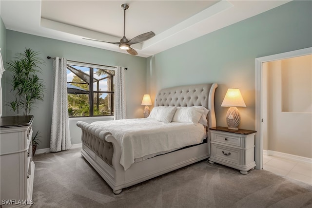 carpeted bedroom with ceiling fan and a tray ceiling