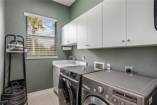 laundry area with sink, light tile patterned floors, cabinets, and independent washer and dryer