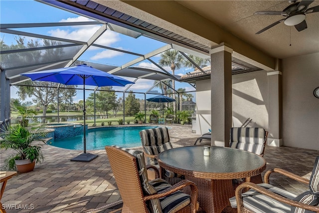 view of pool featuring glass enclosure, a water view, ceiling fan, an in ground hot tub, and a patio area