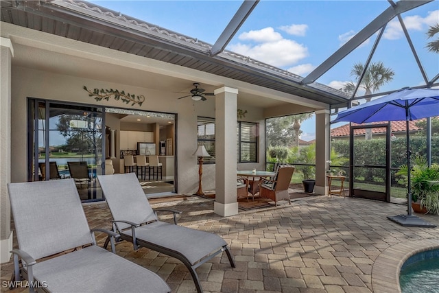 view of patio featuring an outdoor bar, ceiling fan, and a lanai