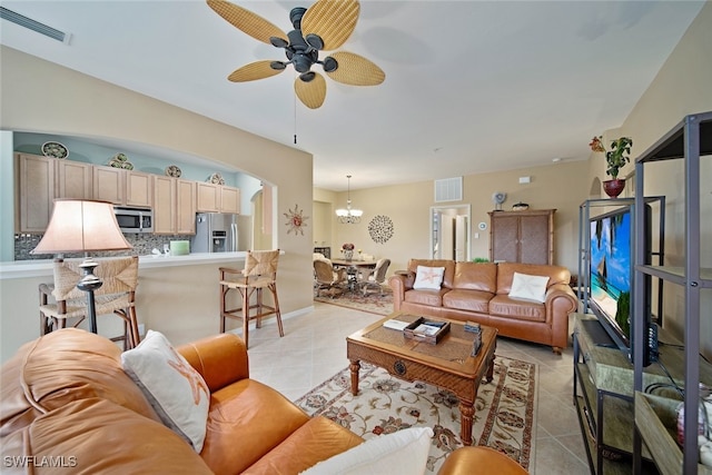 tiled living room featuring ceiling fan with notable chandelier