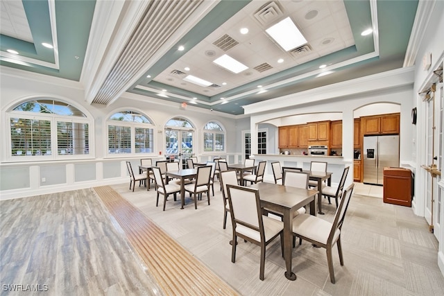 dining room featuring a raised ceiling, crown molding, and a wealth of natural light