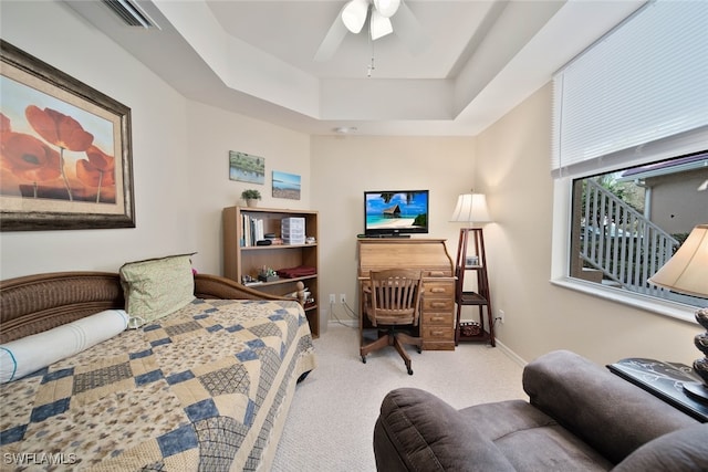 bedroom featuring a raised ceiling, ceiling fan, and light colored carpet