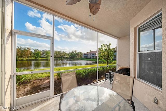 sunroom featuring ceiling fan and a water view