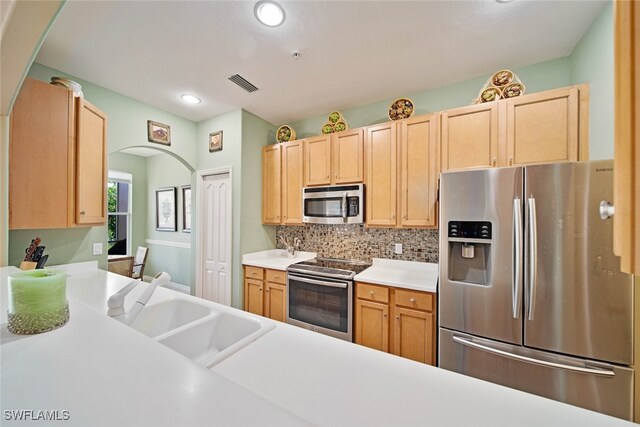 kitchen with decorative backsplash, appliances with stainless steel finishes, light brown cabinetry, and sink