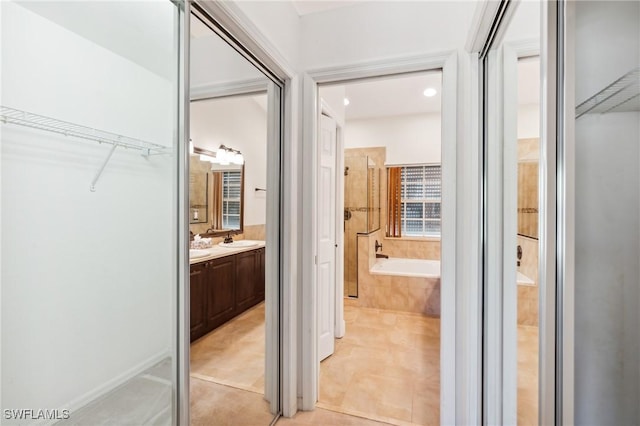 bathroom with tiled bath, vanity, and tile patterned floors