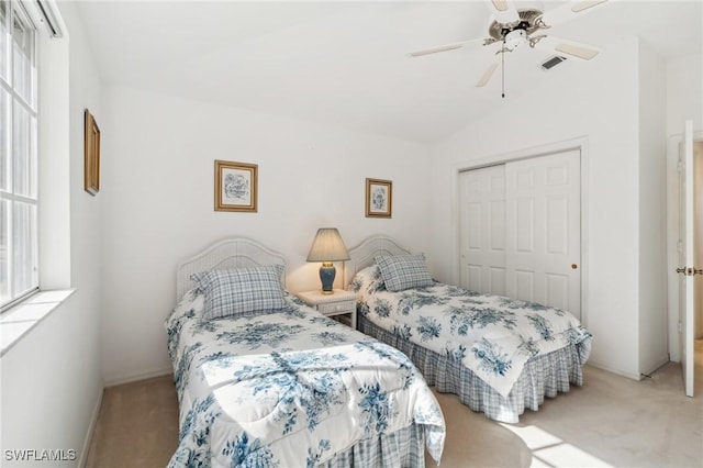 bedroom featuring ceiling fan, a closet, light carpet, and vaulted ceiling