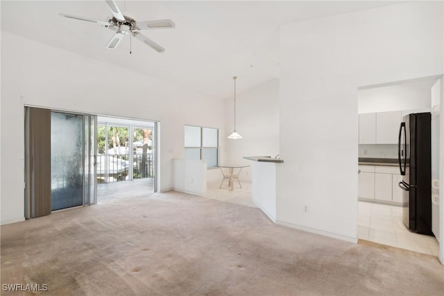 unfurnished living room featuring high vaulted ceiling, light colored carpet, and ceiling fan