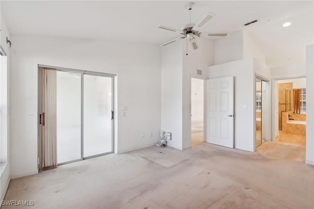 unfurnished bedroom with ceiling fan, light carpet, connected bathroom, and high vaulted ceiling