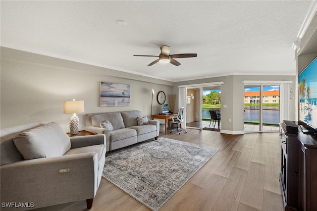 living room with a textured ceiling, light hardwood / wood-style floors, ceiling fan, and ornamental molding