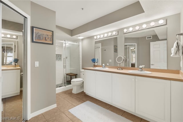 bathroom with tile patterned flooring, vanity, toilet, and a shower with door