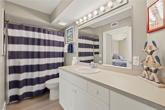 bathroom featuring a shower with shower curtain, hardwood / wood-style floors, vanity, and toilet