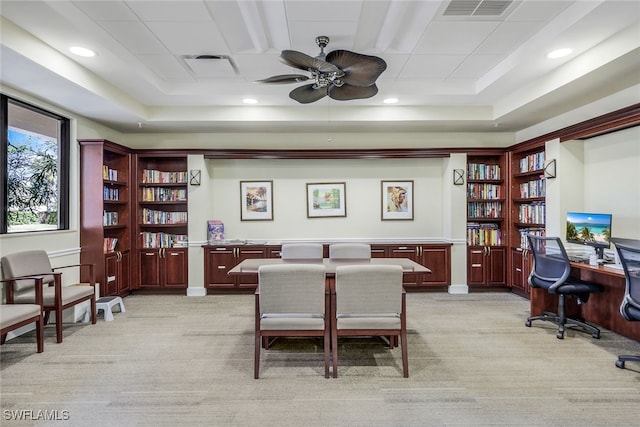 home office with ceiling fan, light carpet, and a tray ceiling