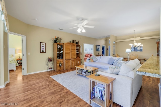 living room with hardwood / wood-style flooring and ceiling fan with notable chandelier