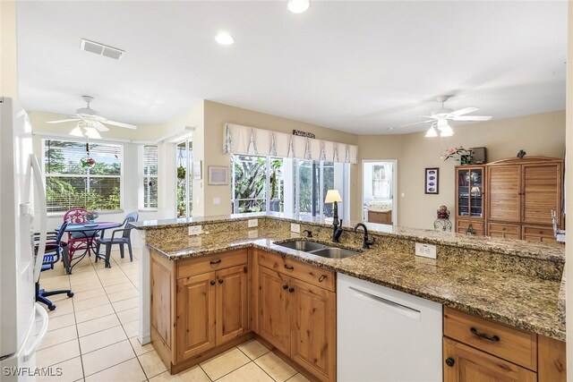 kitchen featuring light tile patterned floors, white appliances, stone countertops, and sink