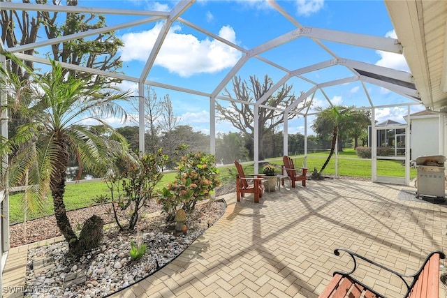 view of patio featuring glass enclosure and a grill