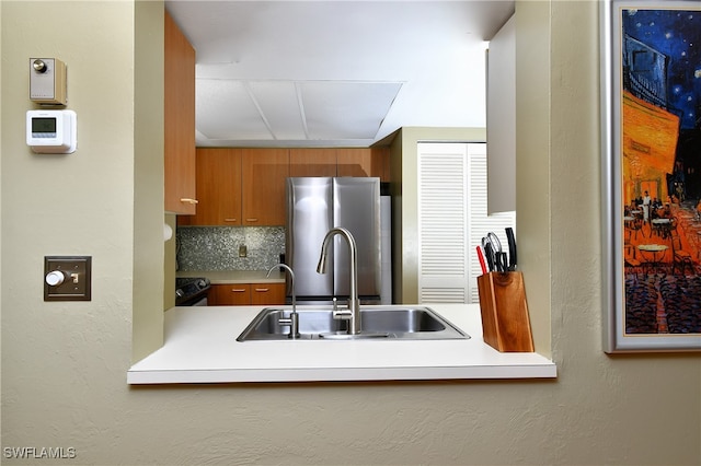 kitchen with electric range oven, sink, stainless steel refrigerator, and tasteful backsplash