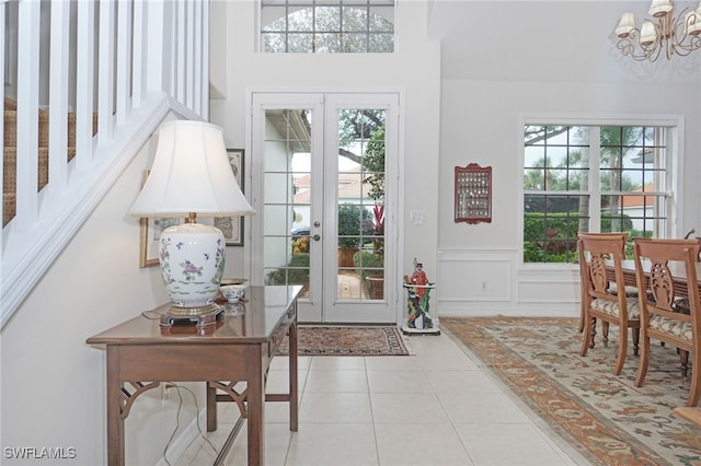 foyer with french doors, light tile patterned floors, and a chandelier