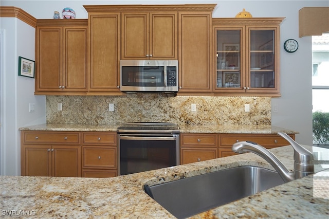 kitchen featuring decorative backsplash, light stone countertops, sink, and stainless steel appliances