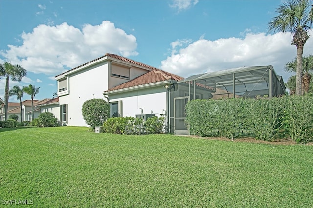 back of house featuring a lanai and a lawn