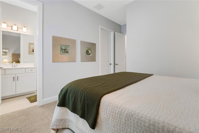 carpeted bedroom with ensuite bathroom and sink